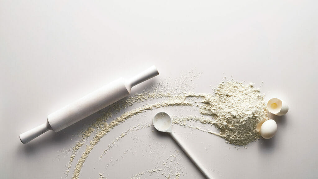 Rolling pin, flour, and eggs on a clean surface, representing baking and cooking creativity.