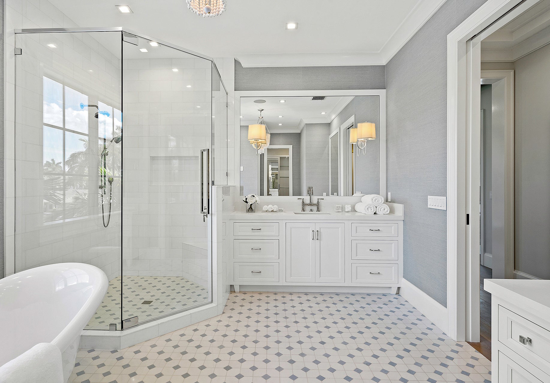 Modern bathroom with glass shower, elegant vanity, and stylish decor, featuring light gray walls and patterned tile flooring.