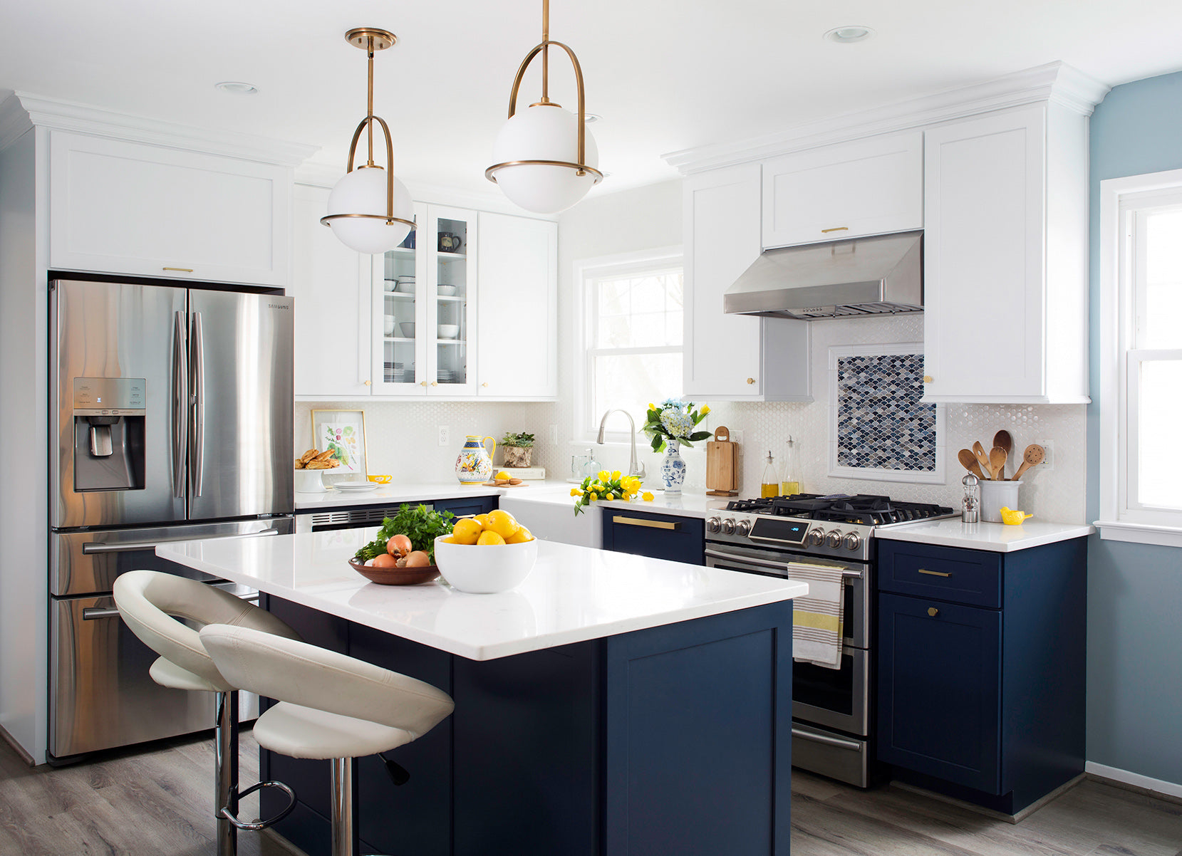 Modern kitchen with Shiloh cabinets, navy blue island, stainless steel appliances, and bright natural light.