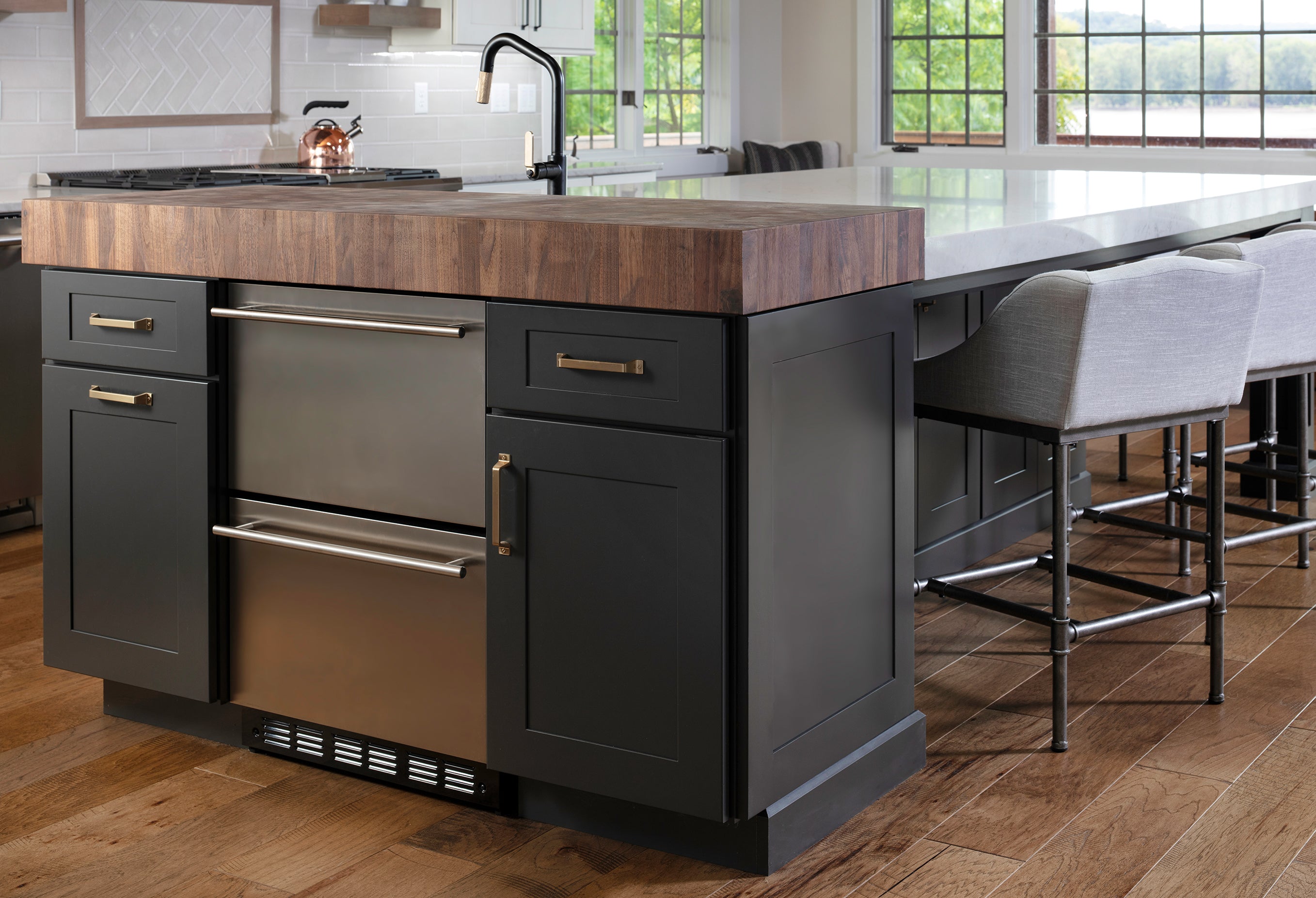 Customizable Shiloh kitchen island with dark cabinets, modern appliances, and wooden countertop in a bright kitchen setting.