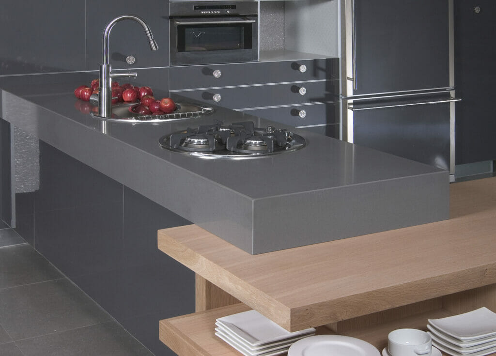 Modern kitchen with a sleek concrete island, gas burners, and wooden bar seating, showcasing industrial design aesthetics.