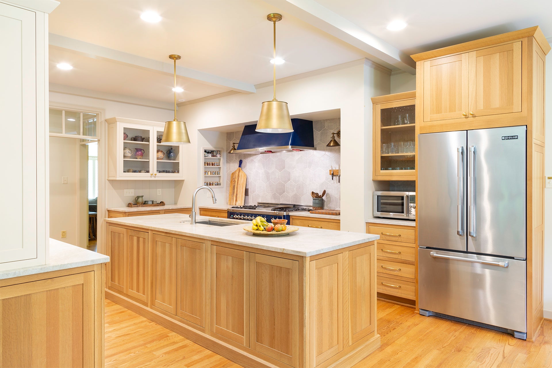 Modern kitchen featuring Shiloh cabinets in natural wood with stylish pendant lights and a spacious island.