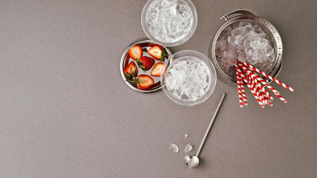 Stylish setup with bowls of ice and strawberries on sleek concrete surface, perfect for refreshments.