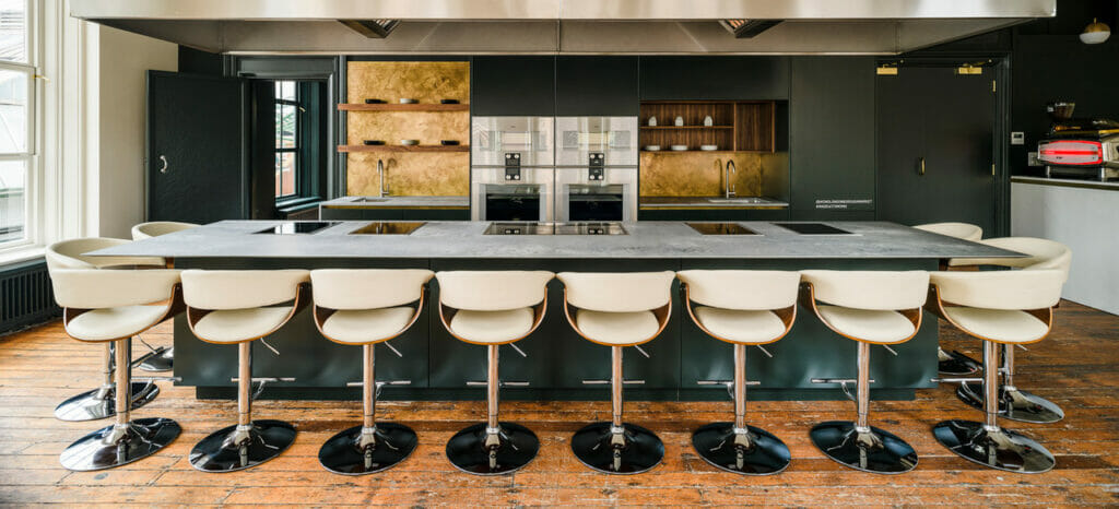 Modern kitchen featuring a large concrete island with sleek bar stools and industrial design elements.