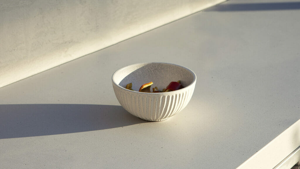 White ribbed bowl with mixed desserts on a smooth concrete surface in soft, natural light.