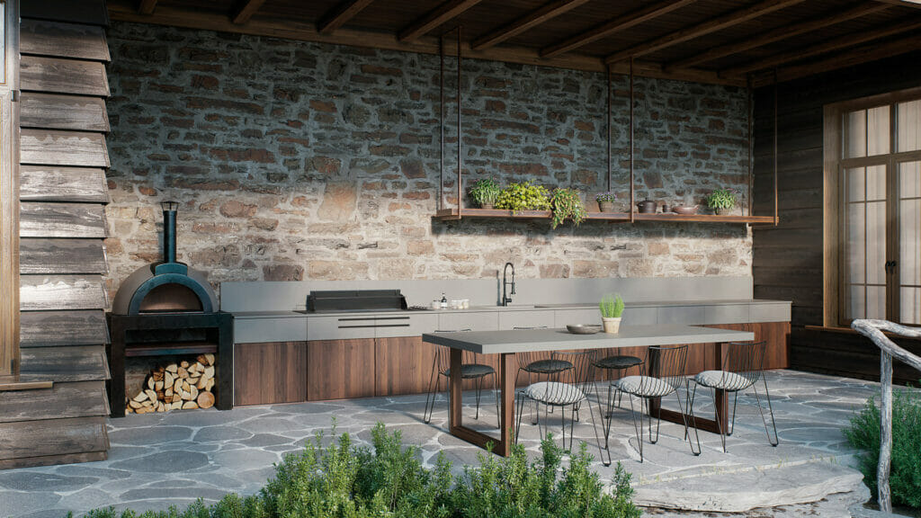 Outdoors kitchen with sleek concrete countertops, rustic stone walls, and wood-fired pizza oven, surrounded by greenery.