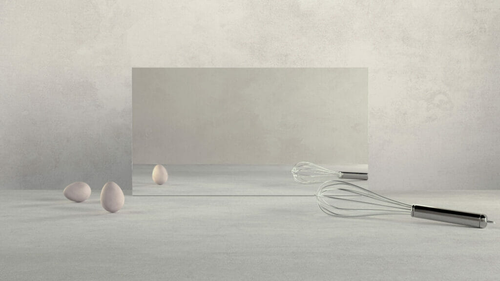 Minimalist kitchen scene with a mirror, whisk, and eggs on a textured surface.