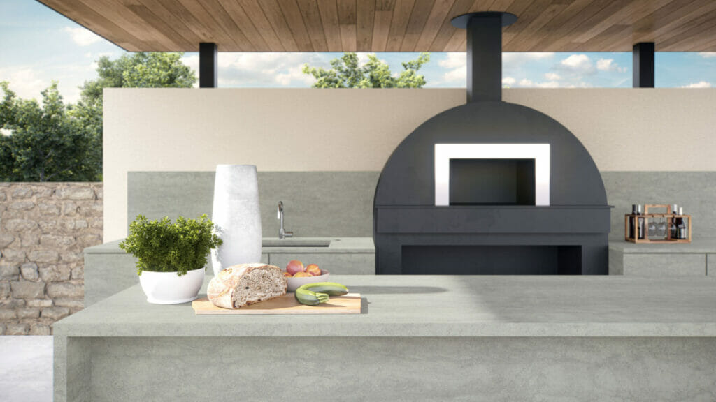 Modern outdoor kitchen featuring 410 Aluminous surface with a black oven, fresh ingredients, and natural elements.