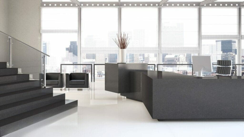 Modern office reception area with sleek black furniture and large windows showcasing skyline views.