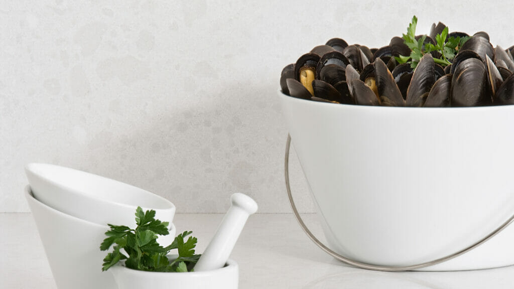 Organic White backdrop featuring a stylish bowl of mussels and white mortar with fresh herbs.