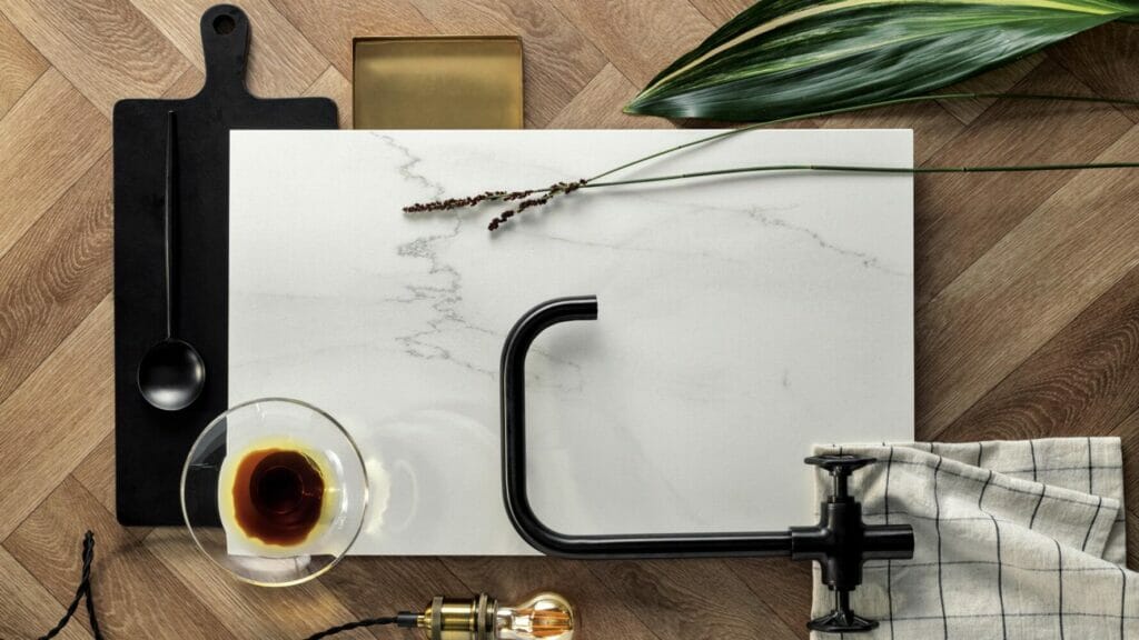 501 Snowdrift marble surface with golden veining, showcased with kitchen accessories and a plant for a stylish aesthetic.