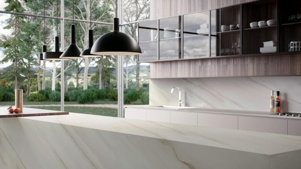 Modern kitchen showcasing elegant white marble countertop and sleek black pendant lights with a scenic outdoor view.