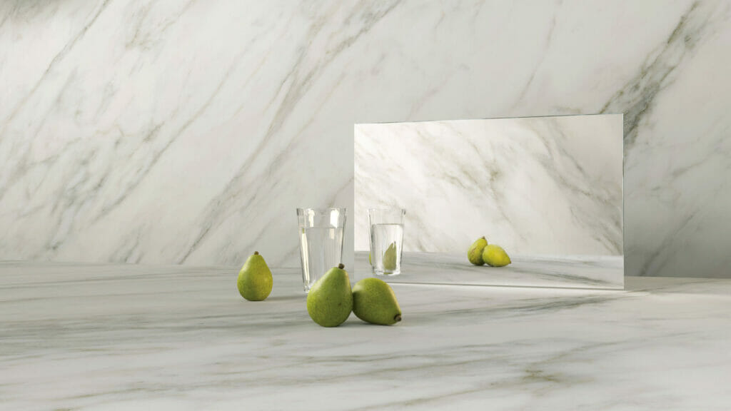 Elegant display of 505 Archetta marble with grey veins, green pears, and glass reflections on a soft ivory-white surface.