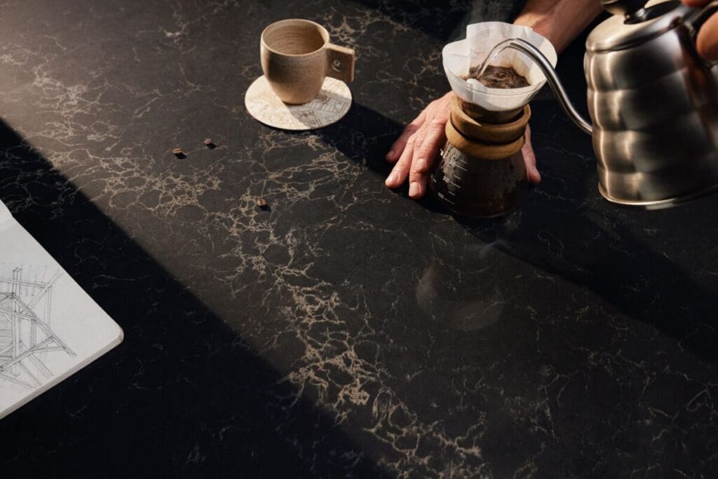 Coffee brewing on a rich, dark marble surface with a kettle and ceramic cup, exuding elegance and warmth.