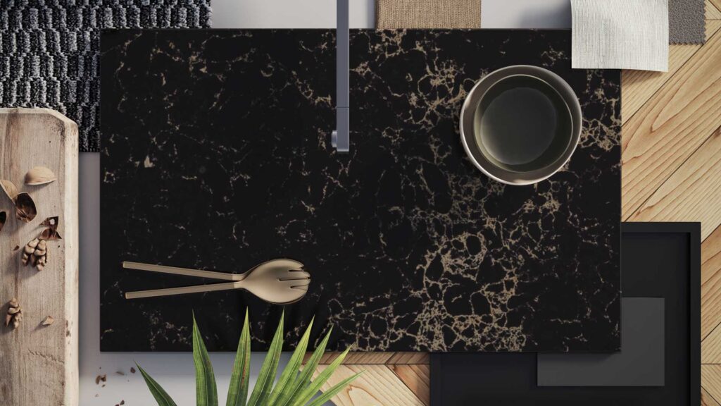 Elegant black marble surface with creamy veins, gold accents, and kitchen utensils creating a chic dining setup.