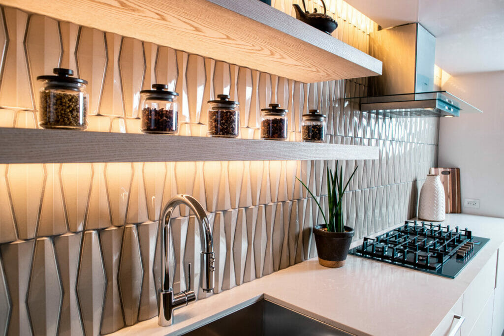 Modern kitchen design featuring textured wall tiles, wooden shelves, and stylish decor elements.
