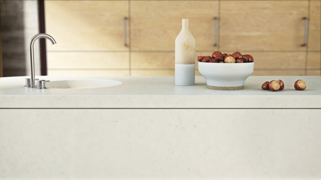 Elegant ivory white countertop featuring powdery-grey veining, adorned with a bowl of apples and a decorative vase.