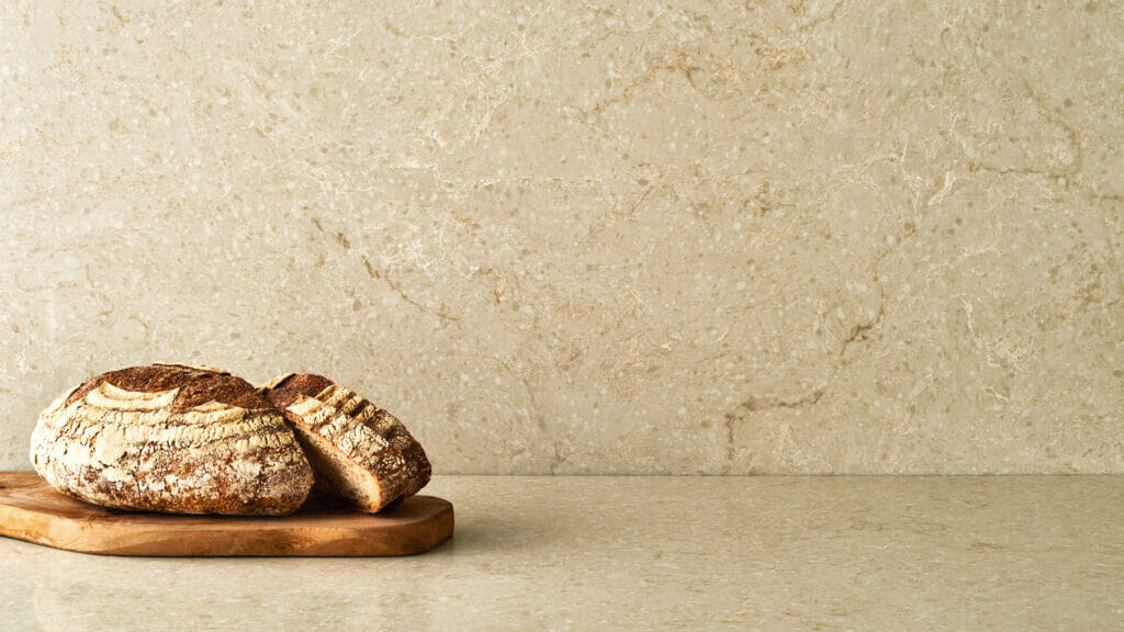 Freshly baked artisan bread on a wooden board against a light textured background.
