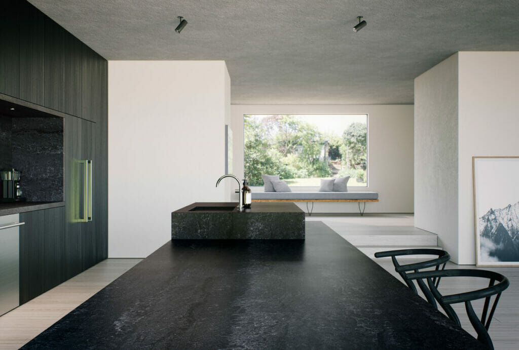 Modern kitchen with textured black countertop and minimalist design, featuring greenery view from large window.