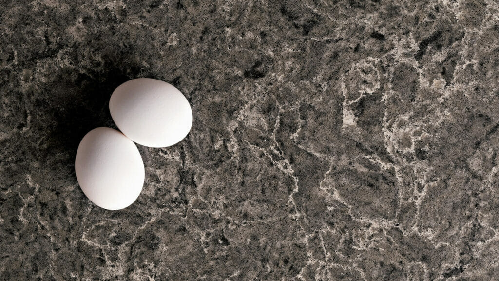 Close-up of two white eggs on a dark coastal grey textured surface, highlighting depth and dynamic contrasts.