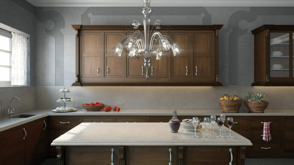Elegant kitchen featuring a glossy countertop, wooden cabinets, modern chandelier, and fresh fruit displays.