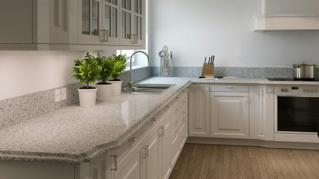 Modern kitchen with light grey granite countertop, white cabinets, and green plants in pots, creating a fresh cooking space.