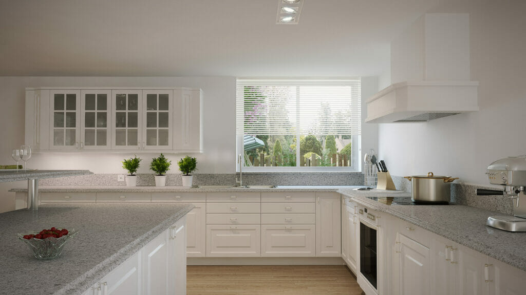 Modern kitchen with light grey countertops, white cabinets, and natural light from a window, creating an inviting atmosphere.