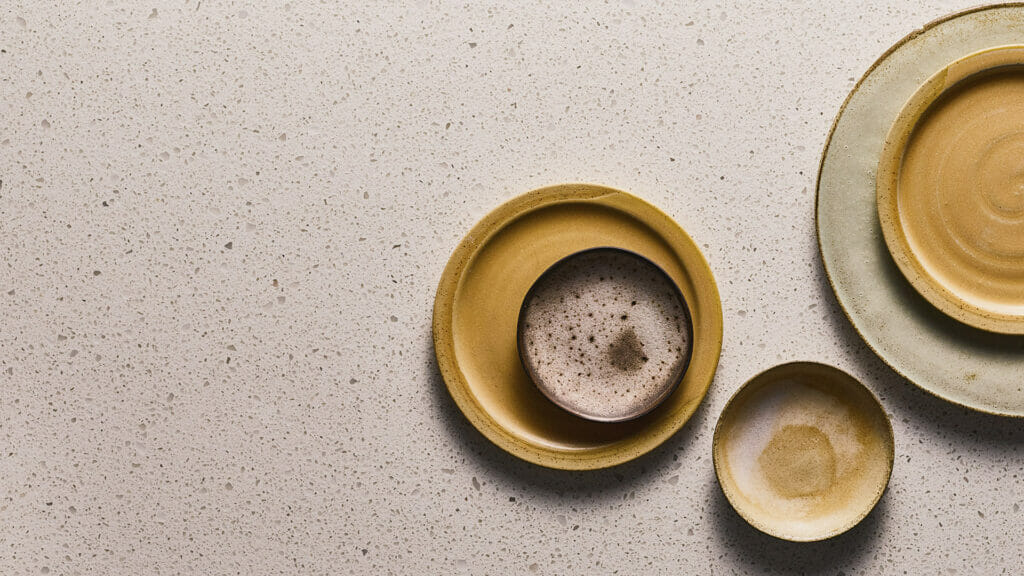 Collection of textured ceramic plates in neutral colors on a white surface, showcasing modern tableware design.