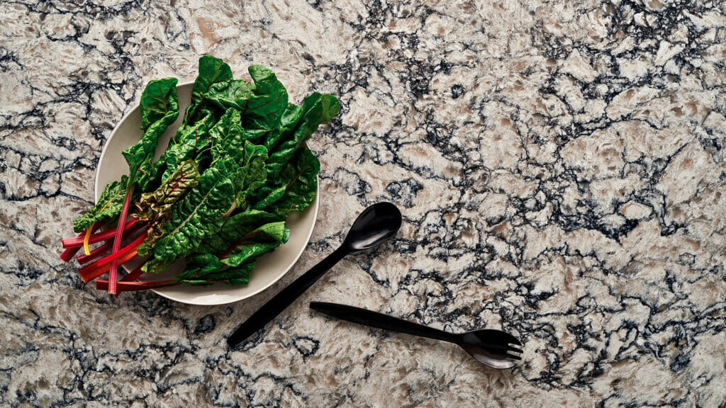 Bowl of fresh greens on a textured granite surface, showcasing dramatic patterns of whites and greys.