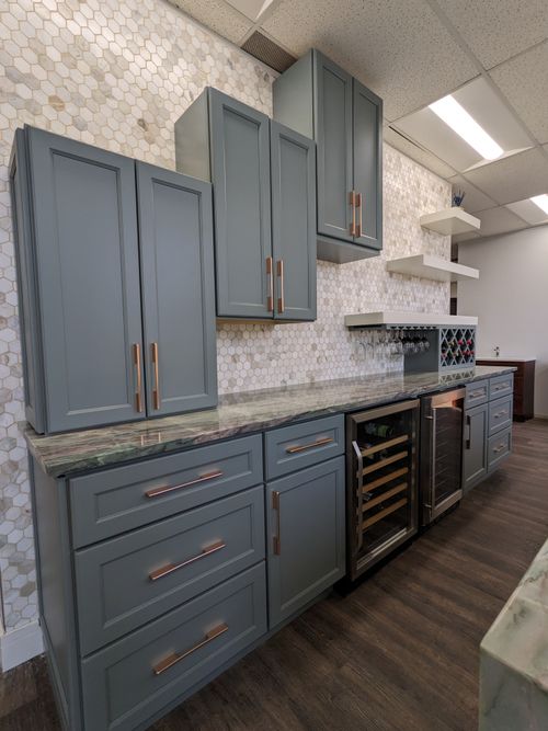 Stylish gray cabinets with bronze handles and a modern countertop featuring a wine cooler and hexagon tile backsplash.