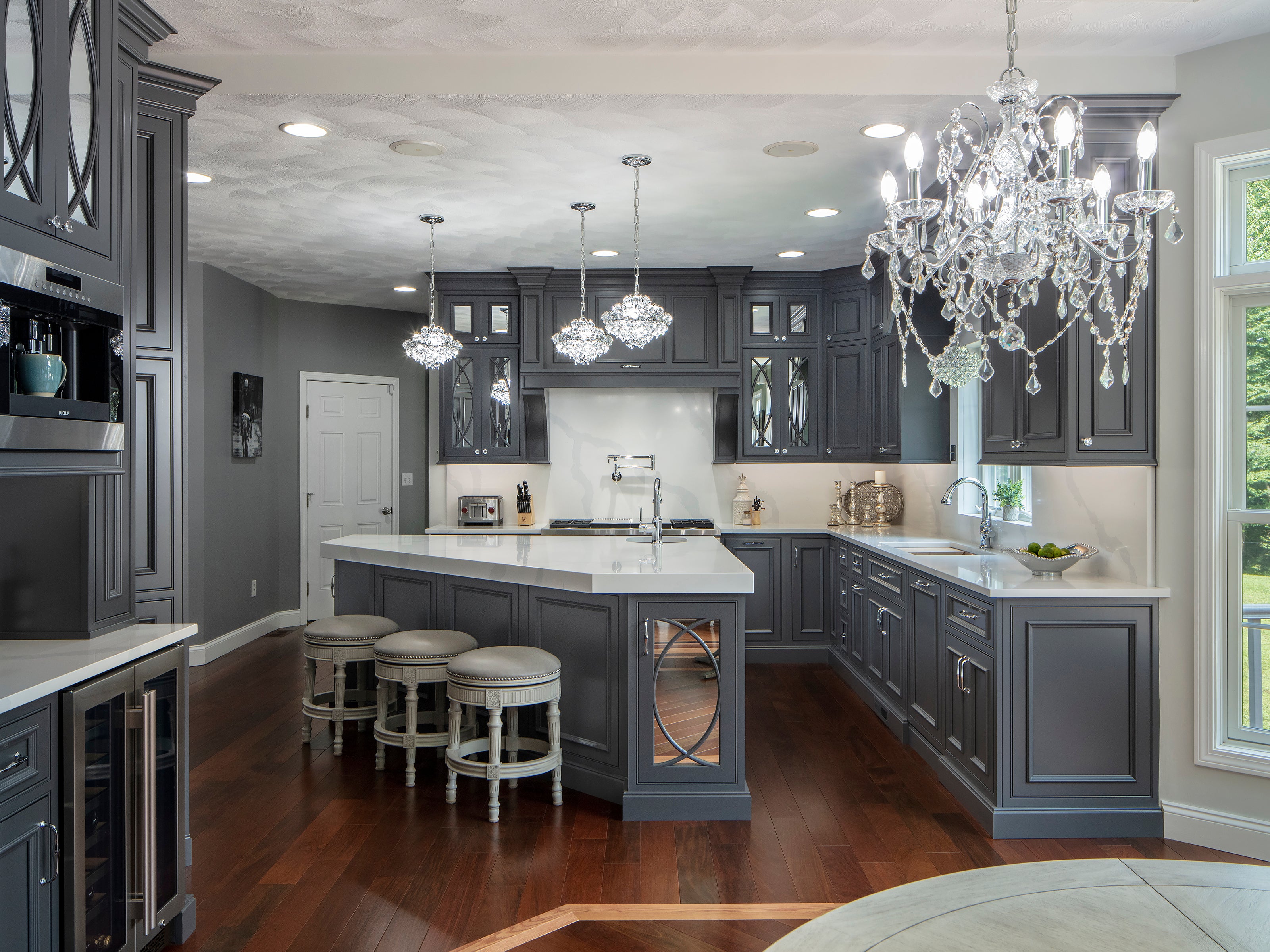 Elegant kitchen featuring Shiloh cabinets in gray with quartz countertops and a chandelier for modern design.