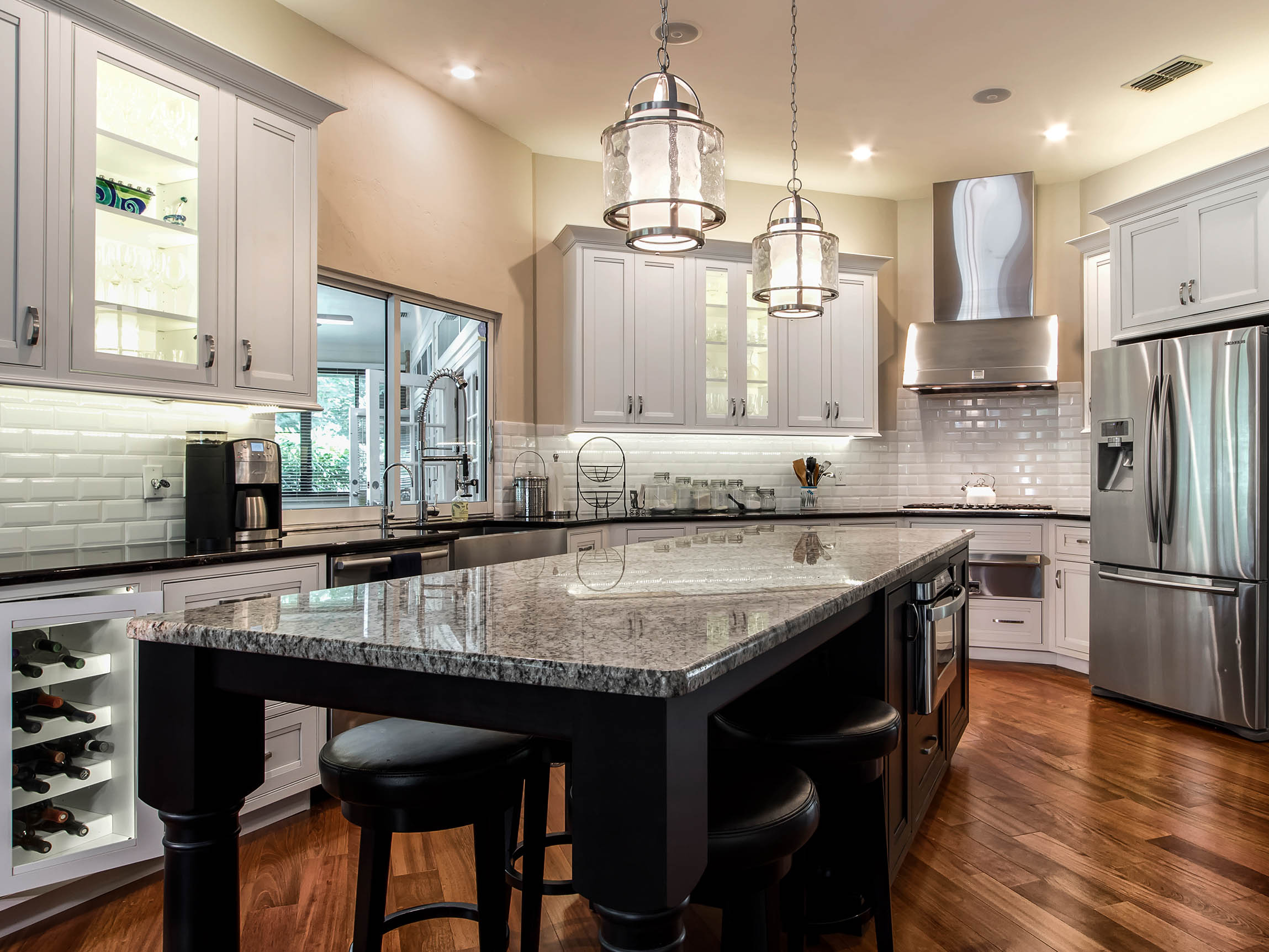 Modern kitchen featuring Shiloh cabinets in white and black, granite countertop, with stylish lighting and stainless steel appliances.