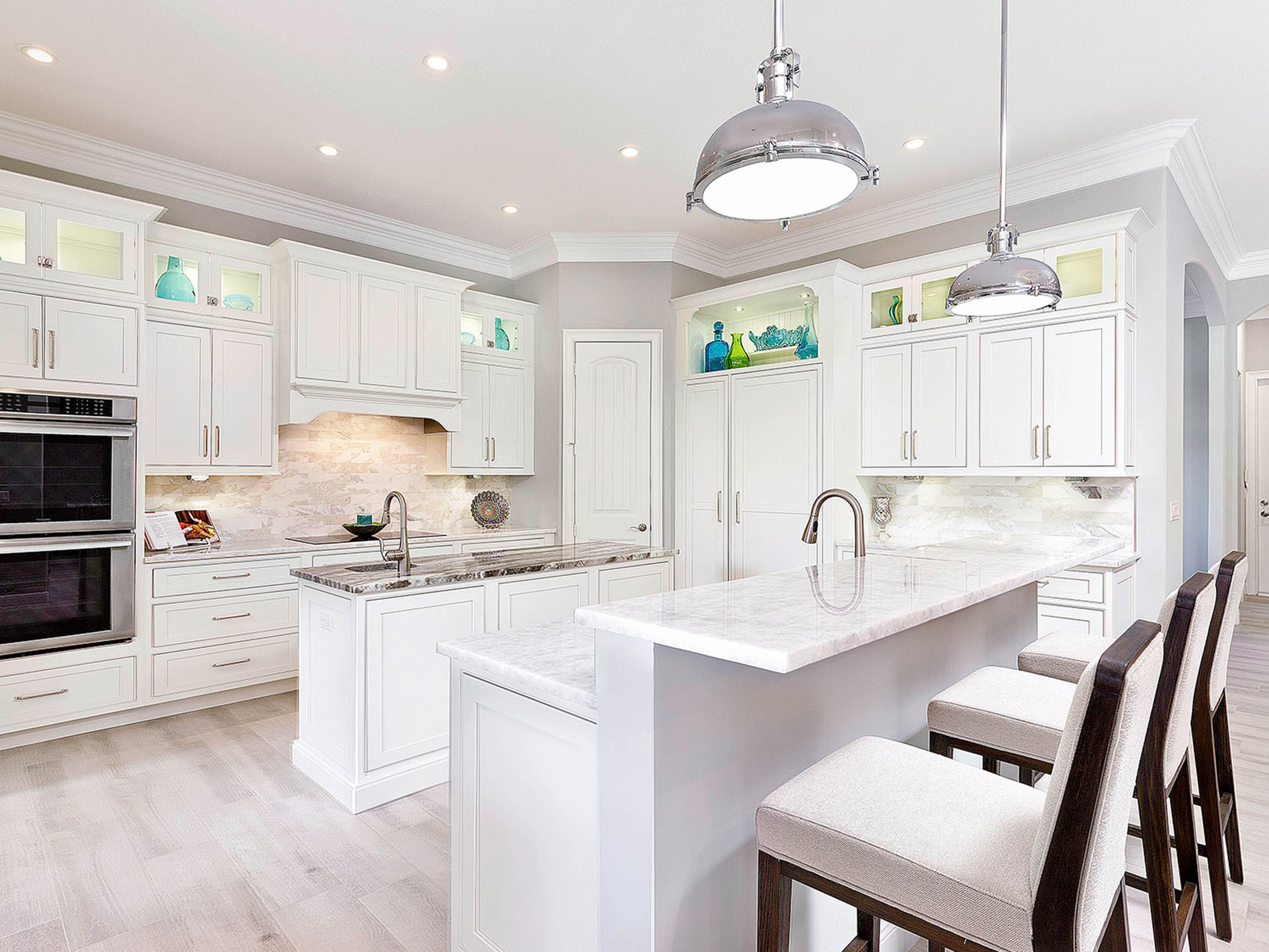 Modern kitchen featuring Shiloh cabinets in white with gray countertops and elegant pendant lighting.