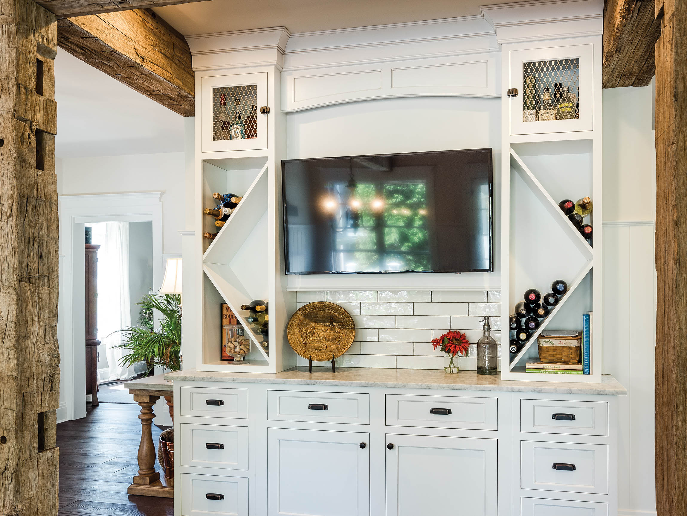Modern white cabinetry design with wine storage, a TV, and decorative accents in a stylish living space.