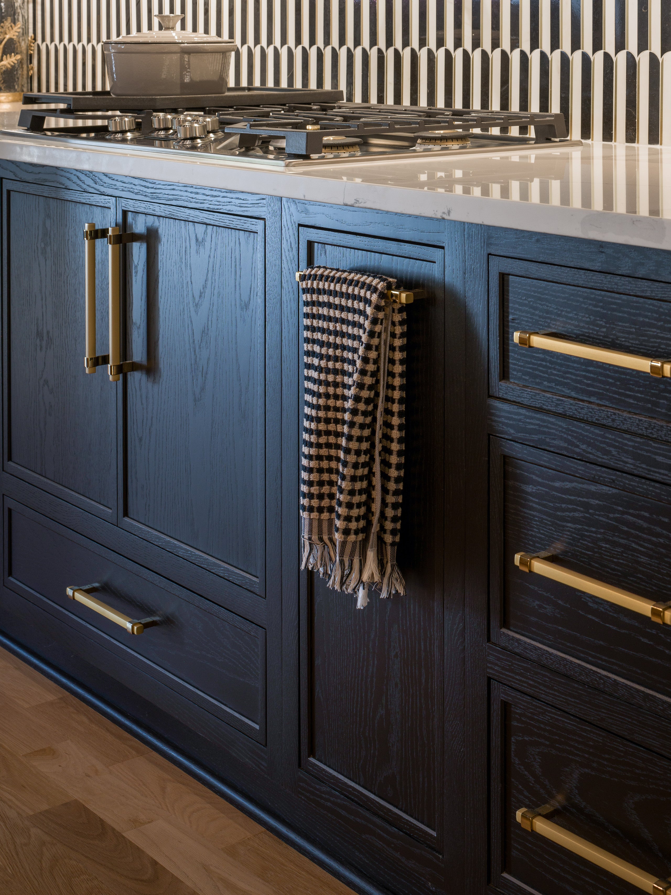 Custom Shiloh kitchen cabinets with dark wood finish and brass hardware, featuring stylish towel hanging.