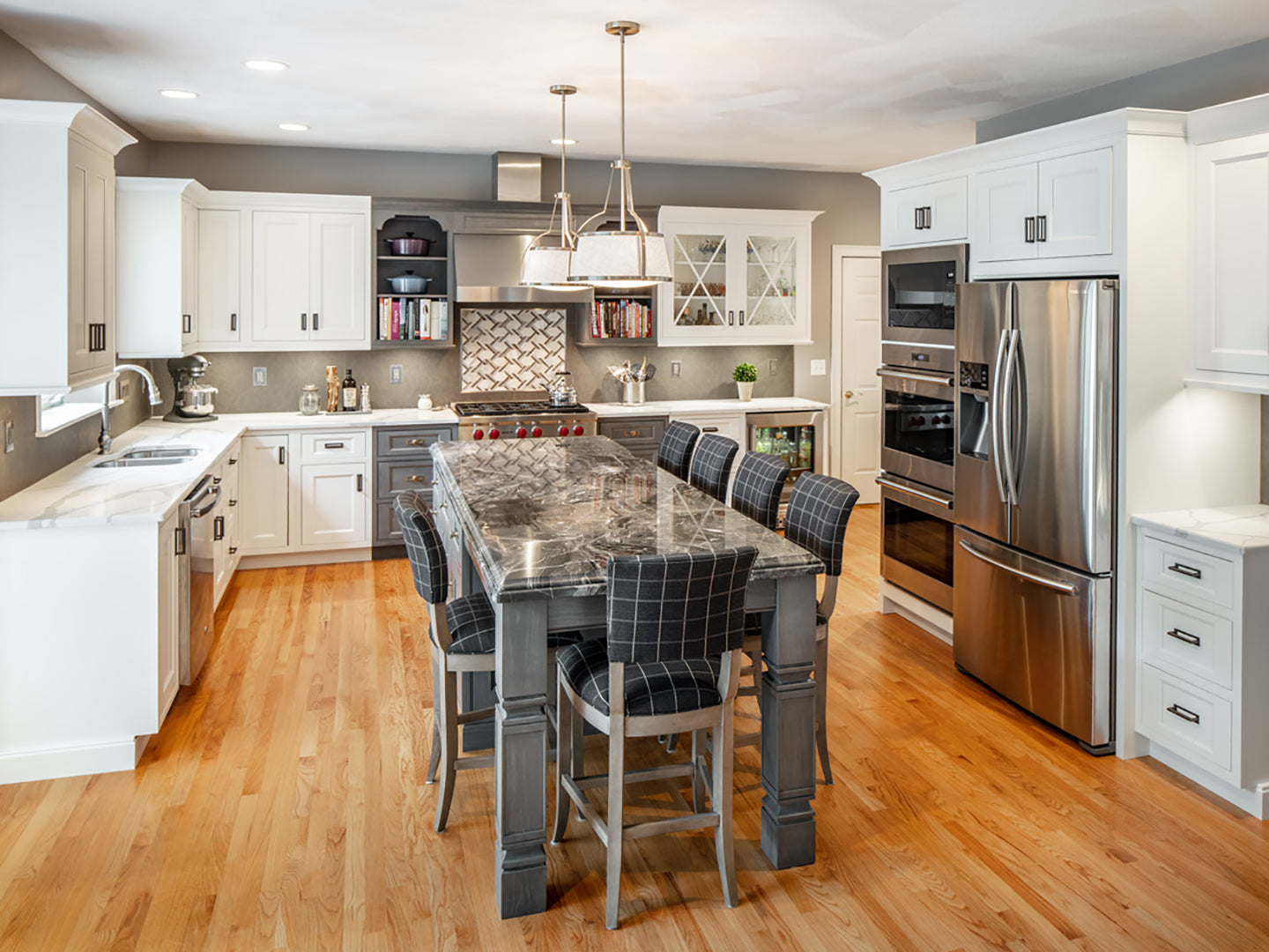 Modern kitchen featuring Shiloh cabinets, stylish island, stainless steel appliances, and warm wooden floors.