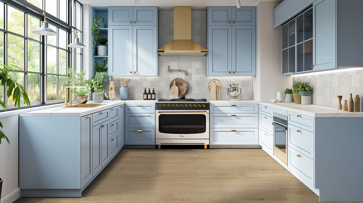 Modern kitchen featuring light blue cabinetry, a gold-accented hood, and ample natural light from large windows.