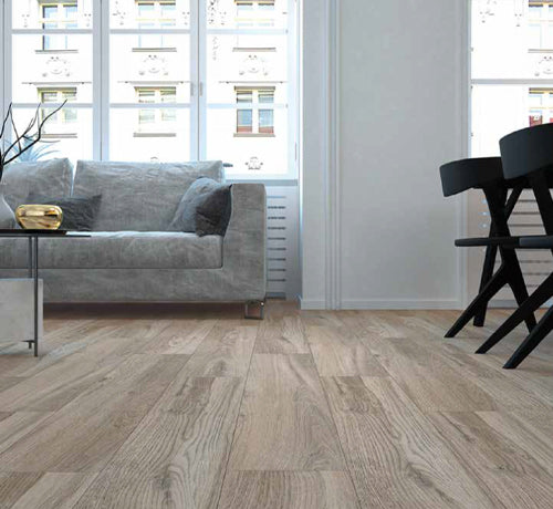 Castagna Olmo Tabacco Bianco porcelain tile flooring in a modern living room with grey sofa and stylish decor.