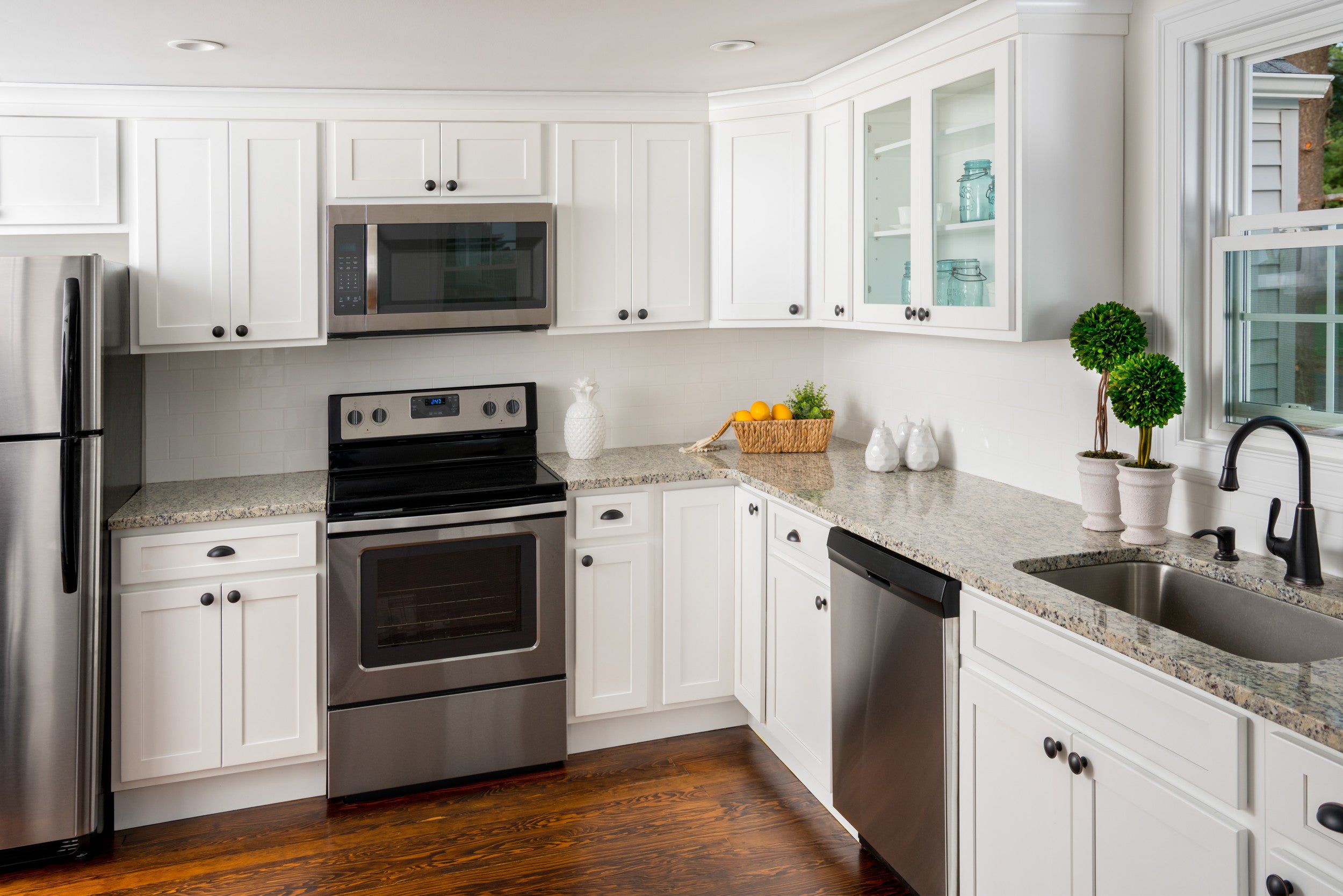 Modern kitchen featuring Quest Discovery Frost cabinets, stainless steel appliances, and granite countertops.