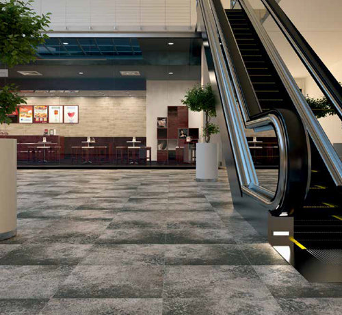 Greggio Beton Bianco Antracite tile flooring in a modern commercial space with an escalator and dining area.
