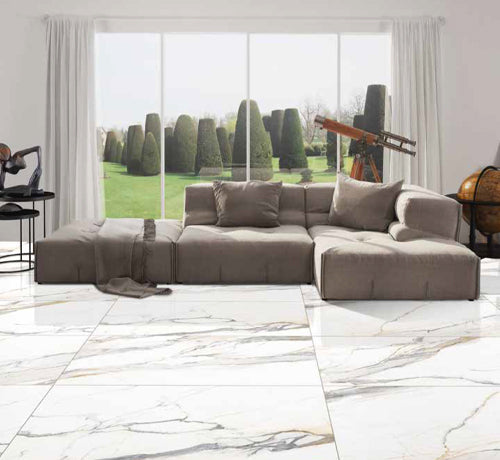 Statuario Elite Tile - Gem showcased in a modern living room with a stylish sofa and a view of landscaped gardens.
