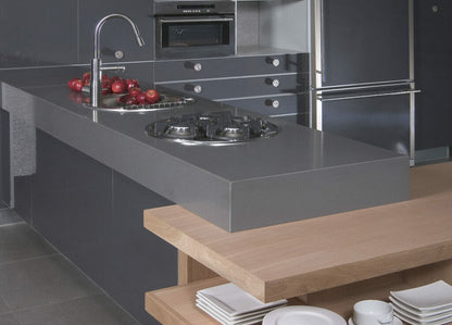 Modern kitchen with a sleek concrete island, gas burners, and wooden bar seating, showcasing industrial design aesthetics.