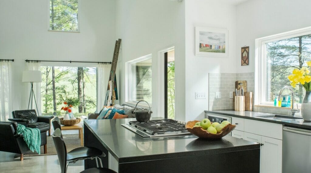 Modern kitchen with sleek black island, bright windows, and natural light showcasing a stylish design.