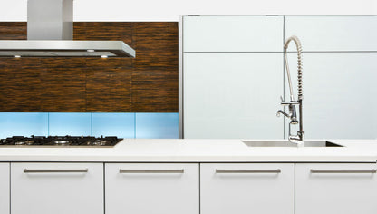 Modern kitchen design with sleek white cabinetry, glass backsplash, and stainless steel fixtures.