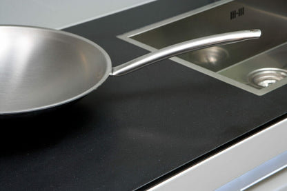 Stainless steel frying pan on sleek 3100 Jet Black countertop, showcasing luxury and sophistication in kitchen design.