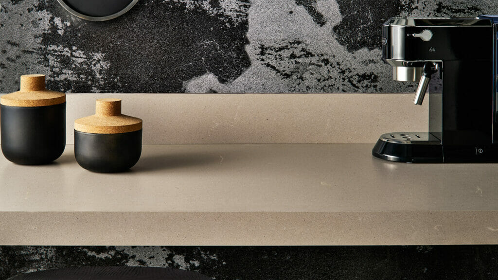 Modern kitchen countertop featuring soft grey 4004 Raw Concrete, black containers, and an espresso machine.