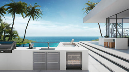 Modern outdoor kitchen with a stunning ocean view, featuring a grill and sleek cabinetry, surrounded by palm trees.