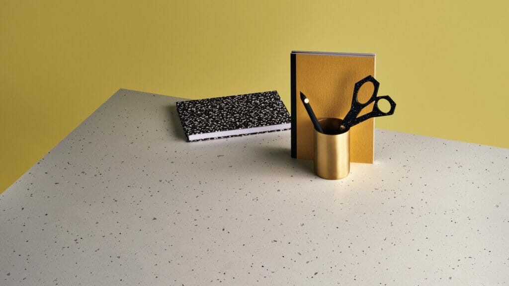 Neutral canvas countertop featuring black basalt and translucent greys, styled with notebooks and scissors.