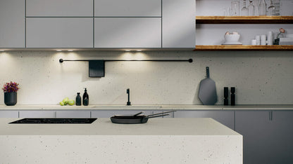 Modern kitchen with neutral terrazzo-style countertop featuring black basalt and greys, complemented by sleek cabinetry.