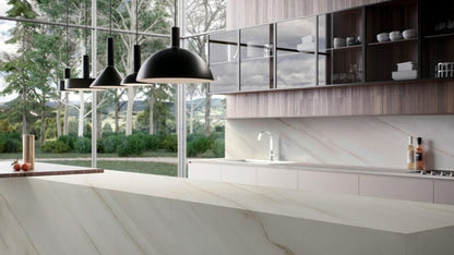 Modern kitchen showcasing elegant white marble countertop and sleek black pendant lights with a scenic outdoor view.